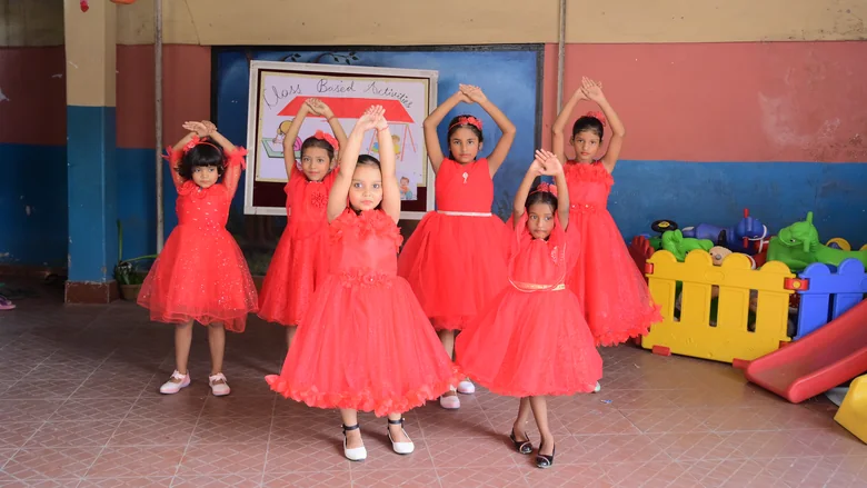 Girls in red dresses performing an action song