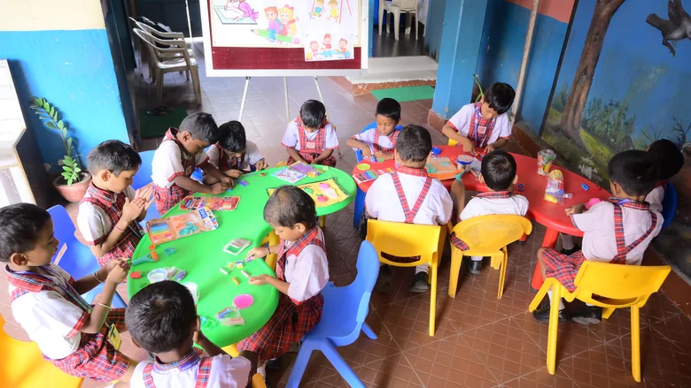 Children busy at two activity tables in a Kiddies Campus classroom